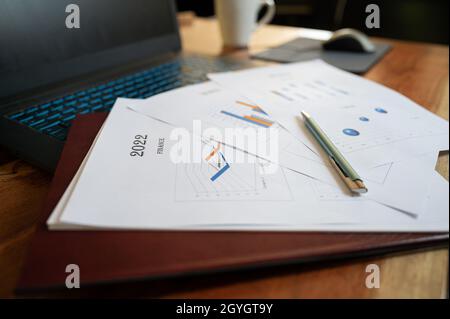 Low angle view of paperwork and documents with financial plan for the year 2022 lying on laptop computer. Stock Photo