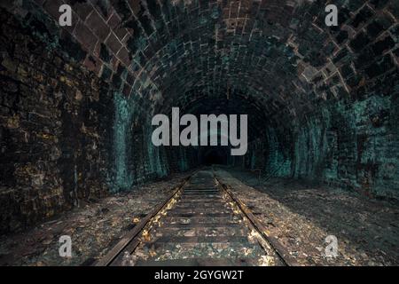 Creepy old abandoned railway tunnel, decayed for decades, a lost place with natural stalactites Stock Photo