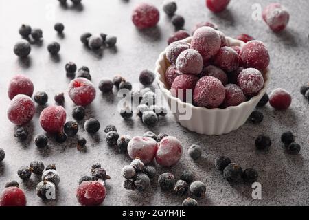 Frozen mix berries red sour cherry and black currant in white bowl on gray background. Close up. Stock Photo