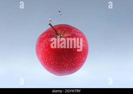 Apple falls into water on a light background. Stock Photo