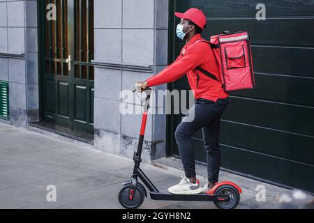African rider delivering meal with electric scooter - Focus on face