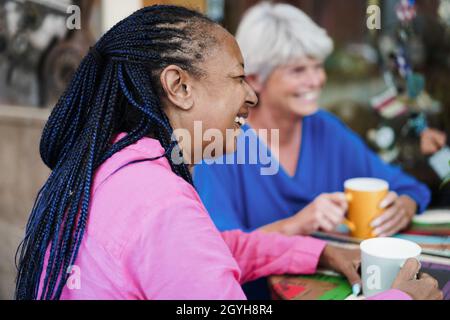 Multiracial senior friends meet and chat at bar outdoor while drinking coffee together Stock Photo
