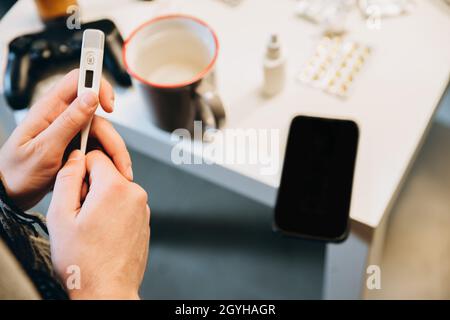 Image of medicines, pills lying on table, boy measuring temperature. Home isolation Stock Photo