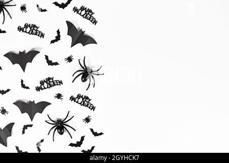 Halloween bats, spiders, flies and Happy Halloween text on side of white background with copy space Stock Photo