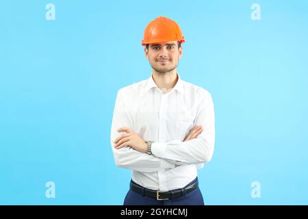 Businessman builder on blue background, front view. Stock Photo