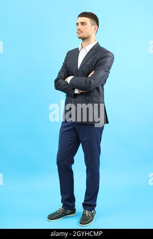 Young businessman in classic suit on blue background. Stock Photo