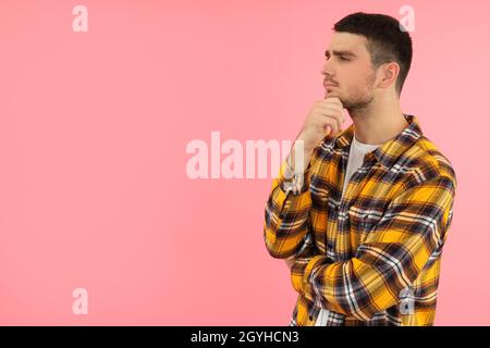 Pensive young man on pink background, space for text. Stock Photo