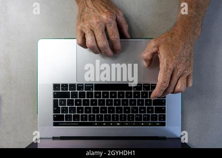 Closeup of hands of an older man working on a laptop Stock Photo