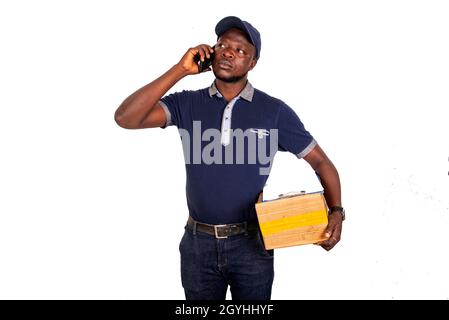 handsome young delivery man talking on mobile phone and holding a cardboard smiling Stock Photo