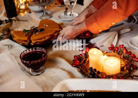 Close-up male hands cutting traditional holiday pumpkin pie during Thanksgiving dinner. Family party at autumn time Stock Photo