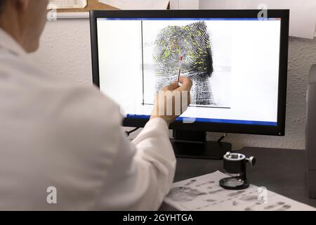 An expert in police science, csi, checks a fingerprint and its matching points on a computer screen Stock Photo
