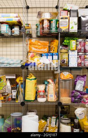 Wire cage larder with produce displayed. Bread, pasta, flour, bisto, tea, pulses. Stock Photo