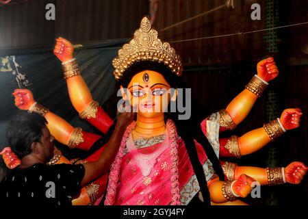 An artisan puts finishing touches to the idol of Goddess Durga, the major deity in Hinduism, as Durga Puja, the biggest religious festival Stock Photo