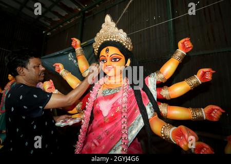 An artisan puts finishing touches to the idol of Goddess Durga, the major deity in Hinduism, as Durga Puja, the biggest religious festival Stock Photo