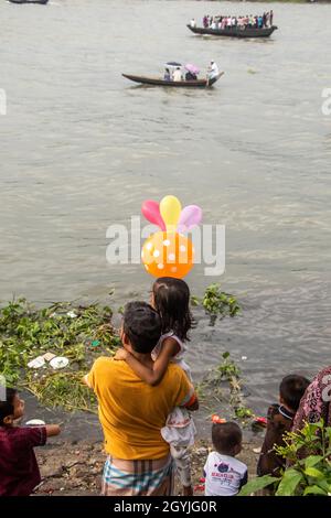 Spectator of boat race enjoying on the riverbank . This image has been captured on September-28- 2021 from Dhaka, Burigongga river, Bangladesh, South Stock Photo