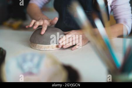 Close up female potter modeling clay bowl in workshop - Artisan work and creative craft concept Stock Photo