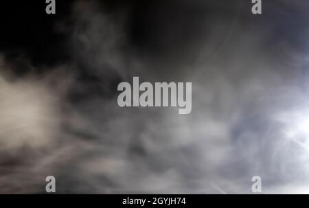 Abstract design of white cloud on a dark background. Blurry motion of smoke. Stock Photo