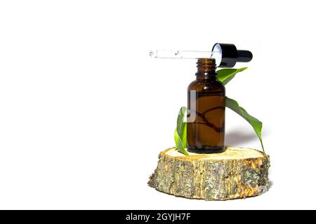 Organic cosmetics. One glass bottle of brown serum with a dropper on a moss-covered wooden podium. Spa cosmetic concept. Place for your text. Stock Photo
