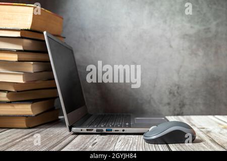 An open laptop on the table near the stack of books. Focus on the bear in front. Place for your text. Stock Photo
