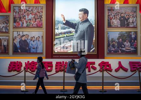 People walk past images showing Chinese President Xi Jinping at the Museum of the Communist Party of China in Beijing, China. 08-Oct-2021 Stock Photo