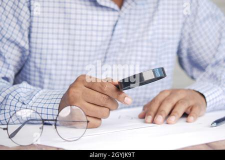 young man using magnifying glass looking something on papers  Stock Photo