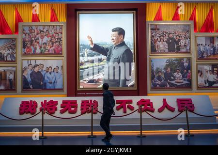 A man walks past images showing Chinese President Xi Jinping at the Museum of the Communist Party of China in Beijing. 08-Oct-2021 Stock Photo