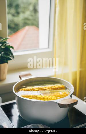 Fresh corn cobs boiling in hot water on stove Stock Photo
