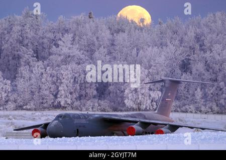 The waning gibbous moon is seen above a U.S. Air Force C 5 Galaxy transport aircraft on the flight line at Joint Base Elmendorf Richardson Alaska Jan 10 2020 as hoarfrost engulfs nearby trees in 16F ...