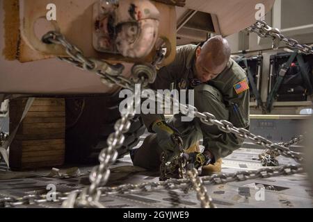 U.S. Air Force Staff Sgt. Andre A. Phillip, a C-17 Globemaster III loadmaster with the 732nd Airlift Squadron, 514th Air Mobility Wing, Joint Base McGuire-Dix-Lakehurst, N.J., tightens chains to secure a forklift to the aircraft prior to take-off, Jan. 10, 2020. Loadmasters must also adjust chains midair due to movement after take-off. (U.S. Air Force photo by Senior Airman Ruben Rios) Stock Photo