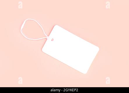 Single blank white paper cloth label or price tag on light pink background top view Stock Photo