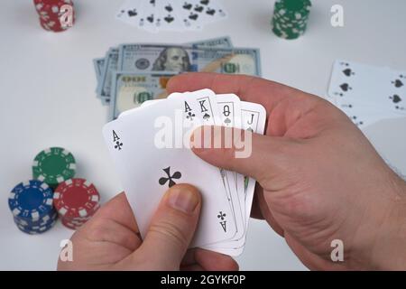 Top view hand showing playing cards. Hands holding playing cards, chip and money, dollars in the background Stock Photo