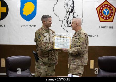 Staff Sgt. Andrew Stoltz with the 108th Sustainment Brigade, Task Force Lincoln, Team Blackhawks, Illinois Army National Guard, receives a commander’s coin of excellence and certificate from Maj. Gen. John P. Sullivan, commander of the 1st Theater Sustainment Command in the US Central Command area of operations, Jan. 21, 2020. Stoltz was selected as the 1st TSC Sustainer of the Week.  Soldiers from Team Blackhawks of the Illinois Army National Guard are executing the logistics advise, assist, and enable mission under the 1st Theater Sustainment Command supporting Combined Joint Task Force — Op Stock Photo