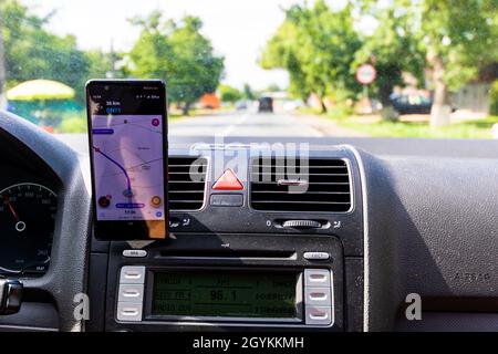 BUCHAREST, ROMANIA - Sep 01, 2021: The Driving and using waze maps application on smartphone on car dashboard Stock Photo