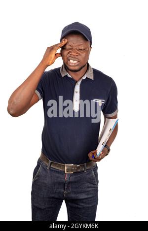 young delivery man standing in blue uniform standing holding a paper clip with document and having headache Stock Photo