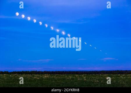 A composite 'time-lapse' blend of the setting Full Moon entering the Earth's umbral shadow on the morning of May 26, 2021. I shot the images during th Stock Photo