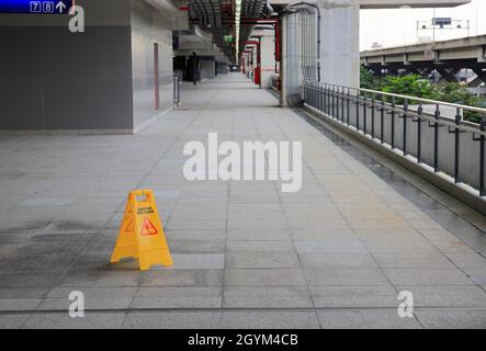 Sign showing warning of caution wet floor, Yellow sign that alerts for wet floor, Warning symbol of slippy floor for pedestrian. Stock Photo