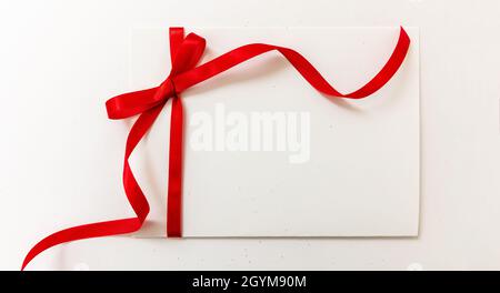 Gift card with red ribbon bow isolated on white background, banner. Empty note paper, copy space, message template. Christmas or valentine present sat Stock Photo