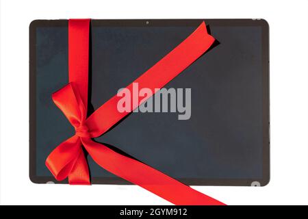 Digital tablet with red ribbon bow, Electronic device Christmas gift isolated on white background. Valentine, holiday present, top view. Stock Photo