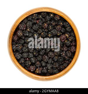 Dried ripe European blackberries in a wooden bowl. Air dried wild brambles, Rubus fruticosus, a sweet fruit, used for tea additive. Stock Photo
