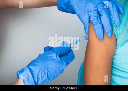 children's nurse injecting arm of little brown girl, doctor's hands with rubber gloves injecting covid-19 or flu vaccine. medical, health and pandemic Stock Photo
