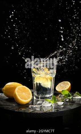splashing lemonade with fresh lemons on black background in studio Stock Photo
