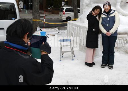 200201-N-RC734-1079    SAPPORO, Japan (Feb. 1, 2020) – Builder 1st Class Jenny Cunningham, assigned to Naval Facilities Engineering Command Far East, Misawa Detachment, poses for a photo with a visitor in front of a snow sculpture created by the Navy Misawa Snow team during the 71st annual Sapporo Snow Festival. This is the 37th year the U.S. Navy has participated in the festival, allowing Sailors a unique opportunity to experience Japanese culture and tradition while strengthening the close friendship between the U.S. Navy and the citizens of Japan. U.S. Navy photo by Chief Mass Communication Stock Photo