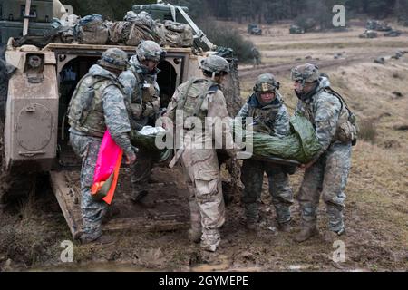 Soldiers from 1st Battalion, 8th Cavalry, 1st Cavalry Division unload patients from an armored troop carrier during Combined Resolve XIII, Feb. 1, 2020, at Hohenfels Training Area.  (U.S. Army photo by Sgt. 1st Class Garrick W. Morgenweck) Stock Photo