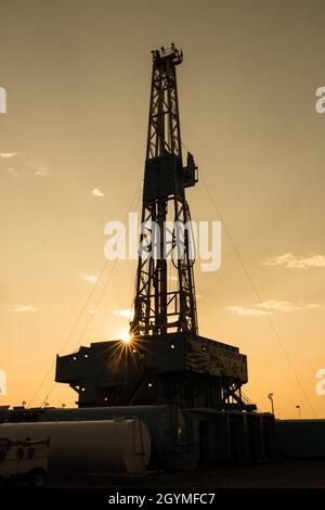 Sunset behind a 3000 hp top drive drilling rig drilling for oil in the Green River Desert in central Utah. Stock Photo