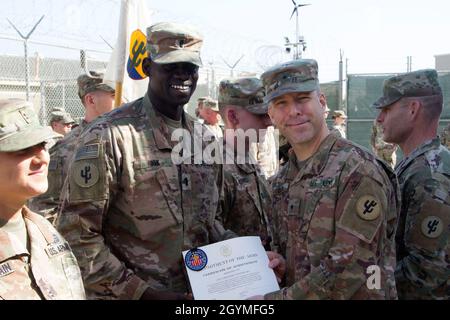 Brig. Gen. Howard Geck, commanding general, poses with 1st Lt. Dau Jok, 103rd Expeditionary Sustainment Command, after presenting him with a Certificate of Achievement and the Army Physical Fitness Badge at Camp Arifjan, Kuwait, Feb. 2, 2020. Soldiers need to score at least 90 points in all three events of the Army Physical Fitness Test to earn the badge. (U.S. Army Reserve photo by Spc. Dakota Vanidestine) Stock Photo