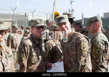 Brig. Gen. Howard Geck, commanding general, poses with Sgt. Julie Lautner, 103rd Expeditionary Sustainment Command, after presenting her with a Certificate of Achievement and the Army Physical Fitness Badge at Camp Arifjan, Kuwait, Feb. 2, 2020. Soldiers need to score at least 90 points in all three events of the Army Physical Fitness Test to earn the badge. (U.S. Army Reserve photo by Spc. Dakota Vanidestine) Stock Photo