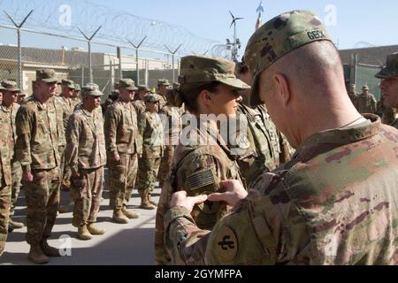 Brig. Gen. Howard Geck, commanding general, 103rd Expeditionary Sustainment Command (ESC), presents Spc. Morgan Welke, 103rd ESC, with a combat patch during an award, patching, and promotion ceremony at Camp Arifjan, Kuwait, Feb. 2, 2020. (U.S. Army Reserve photo by Spc. Dakota Vanidestine) Stock Photo