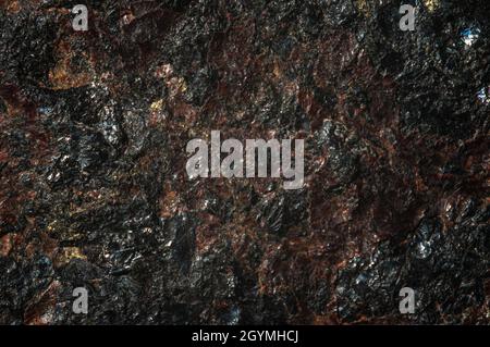 Textured surface of dark natural stone with various inclusions. Abstract background. Stock Photo