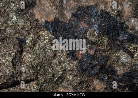 Textured surface of dark natural stone with various inclusions. Abstract background. Stock Photo