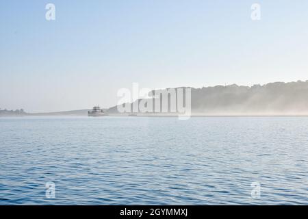 Early summer morning fog scene with tugboat in Port Jefferson Harbor, Long Island, NY. Copy space. Stock Photo